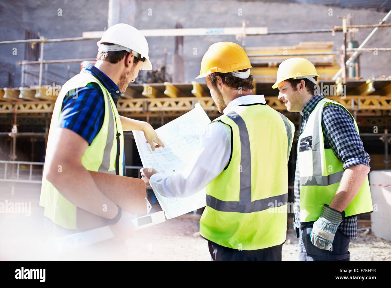 Les travailleurs de la construction et ingénieur reviewing blueprints at construction site Banque D'Images