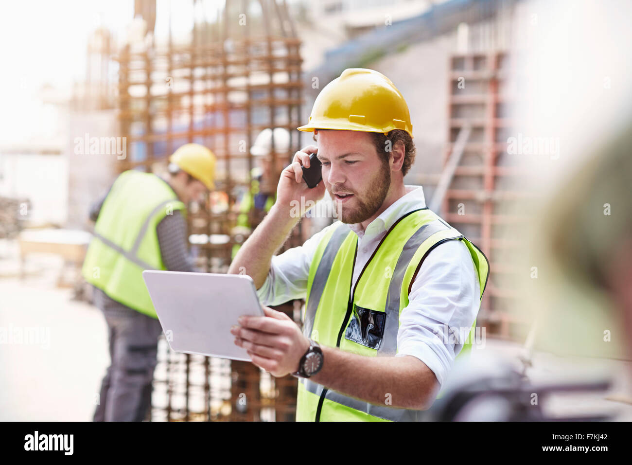 Engineer with digital tablet talking on cell phone at construction site Banque D'Images