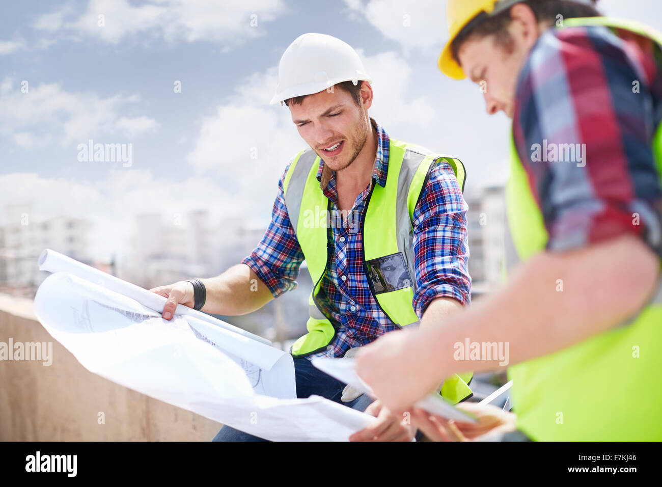 Travailleur de la construction et ingénieur reviewing blueprints at construction site Banque D'Images