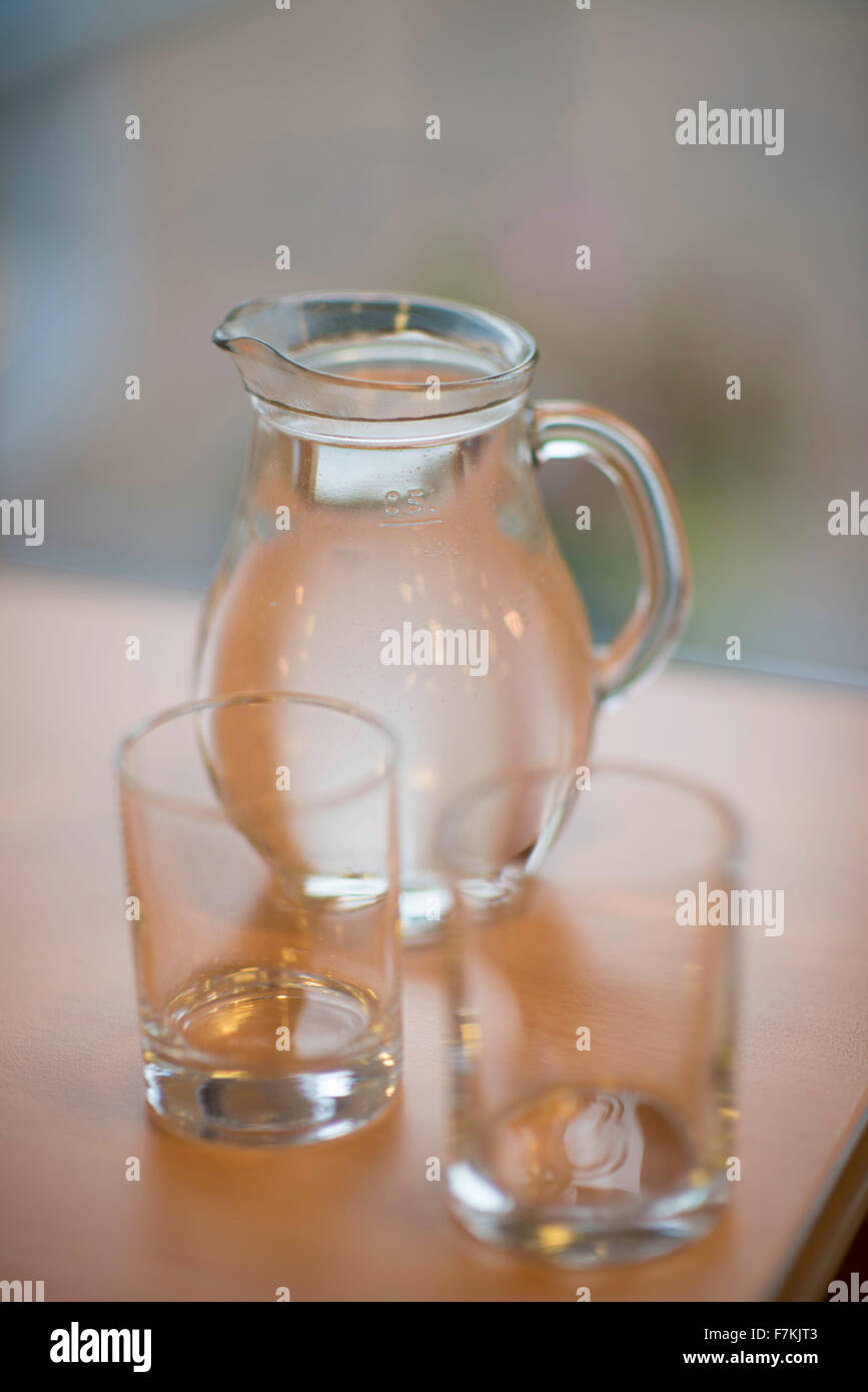 Une cruche d'eau avec deux verres sur une table Banque D'Images