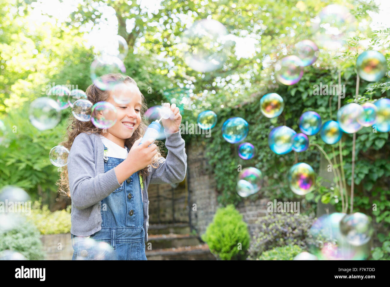 Girl blowing bubbles in backyard Banque D'Images
