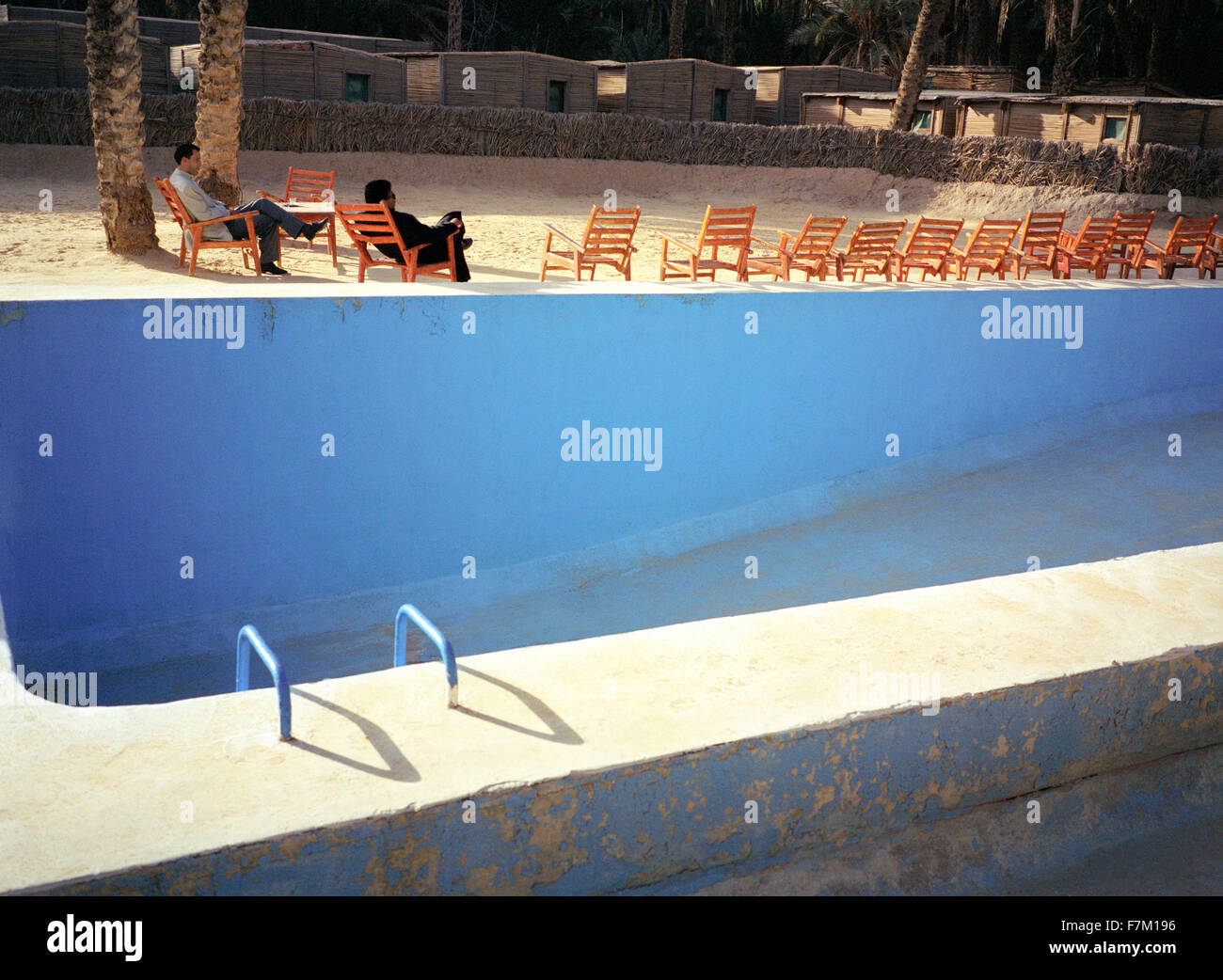 Deux hommes tunisiens se détendre par une piscine vide près de Nefta, Tunisie, Afrique du Nord. Banque D'Images
