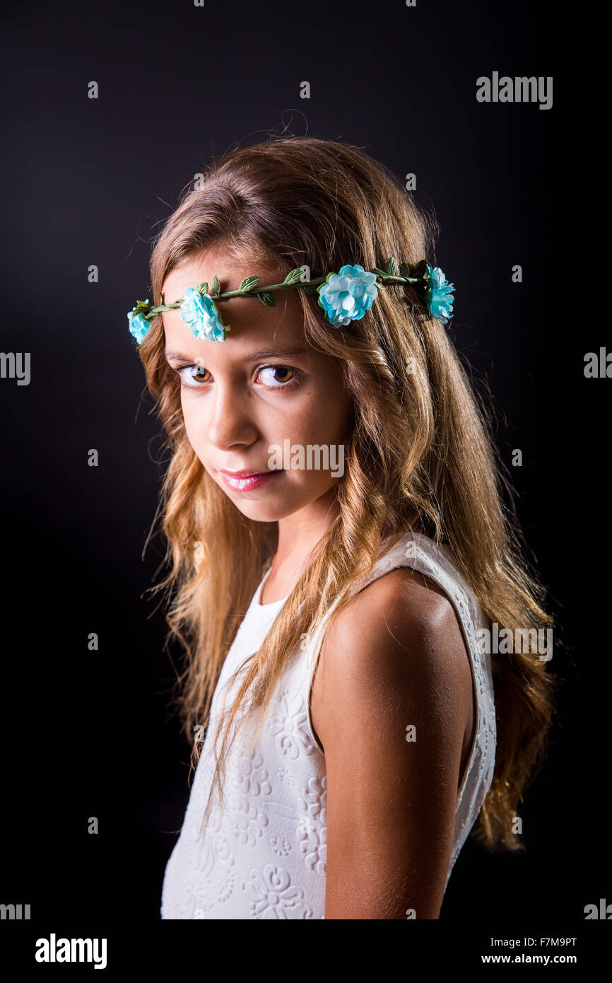 Jeune fille aux cheveux longs et fleur tiare posant avec un regard lucide  sur un fond noir Photo Stock - Alamy