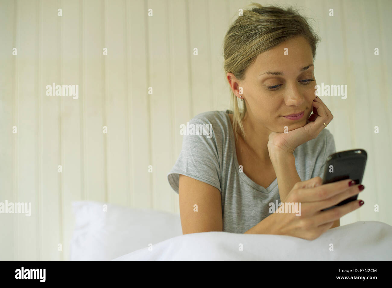 Woman sitting in bed using smartphone Banque D'Images