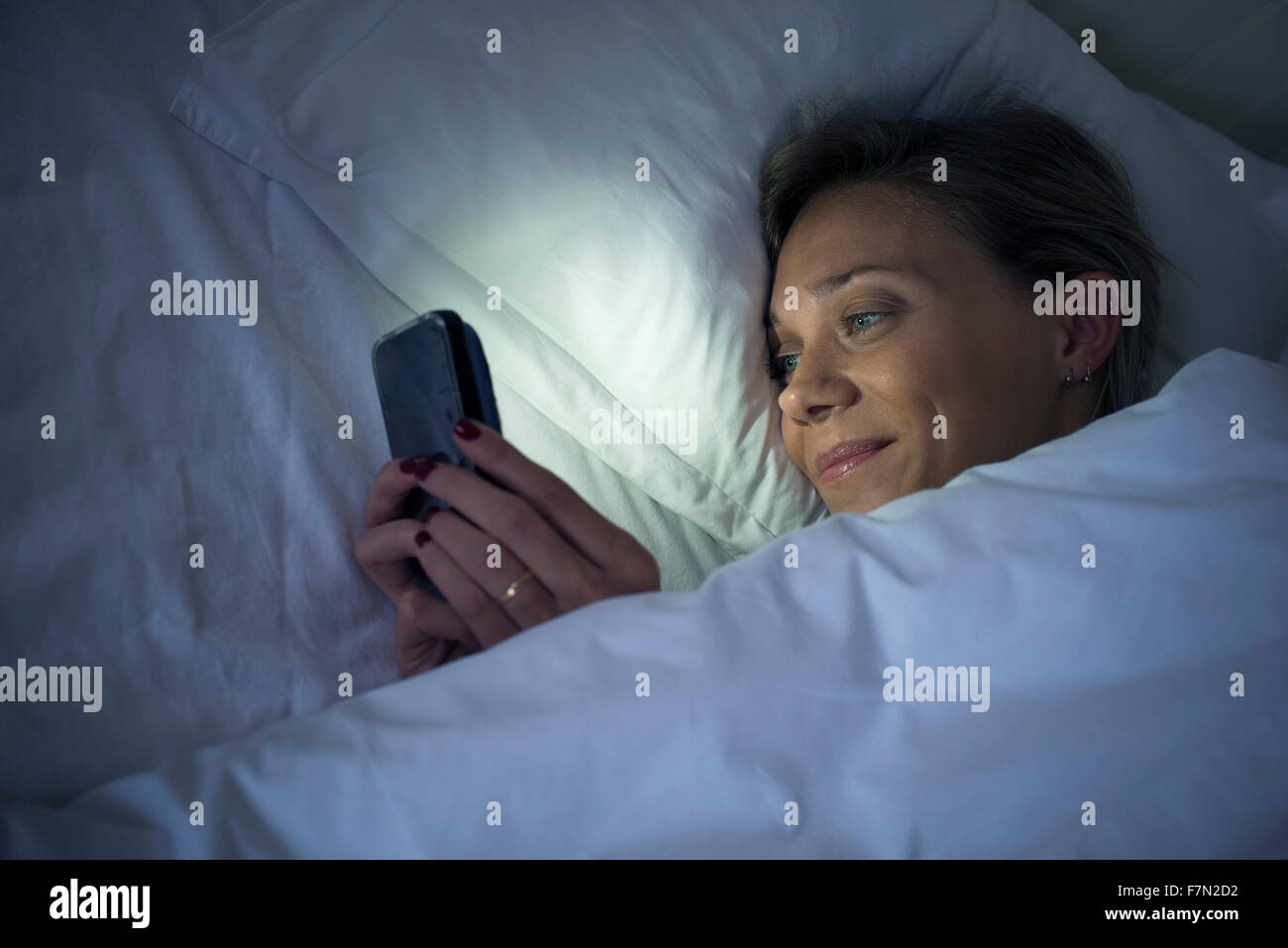 Woman in bed using smartphone Banque D'Images