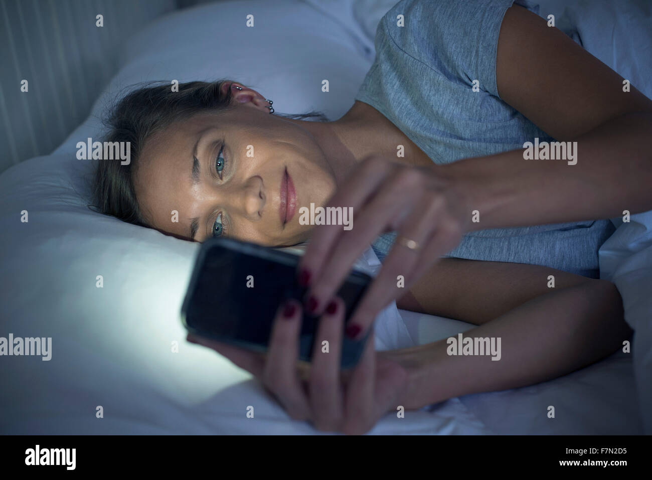 Woman in bed using smartphone Banque D'Images