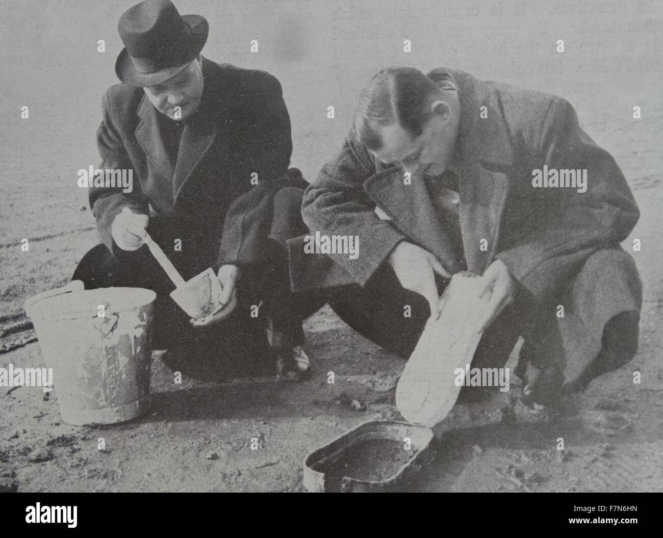 Enquête criminelle (CID) detectives faire un cast d'une empreinte sur la scène de crime, Angleterre 1950 Banque D'Images