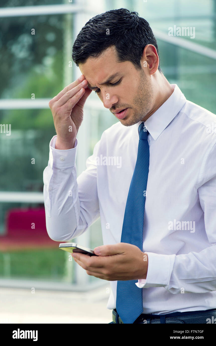 Businessman looking at cell phone avec expression inquiète Banque D'Images