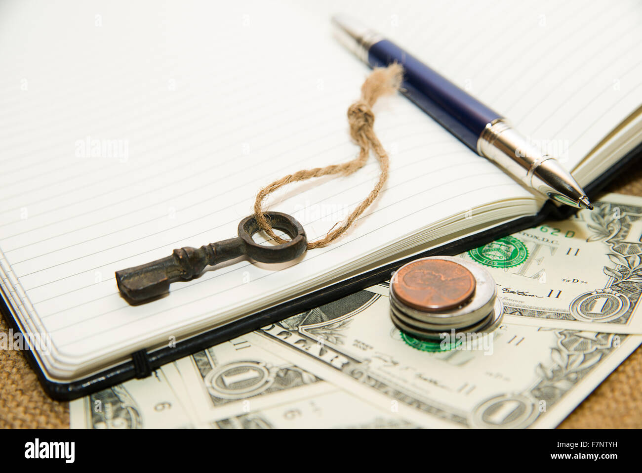 Ordinateur portable ouvert avec une feuille blanche, un stylo et de l'argent sur le tissu ancien Banque D'Images