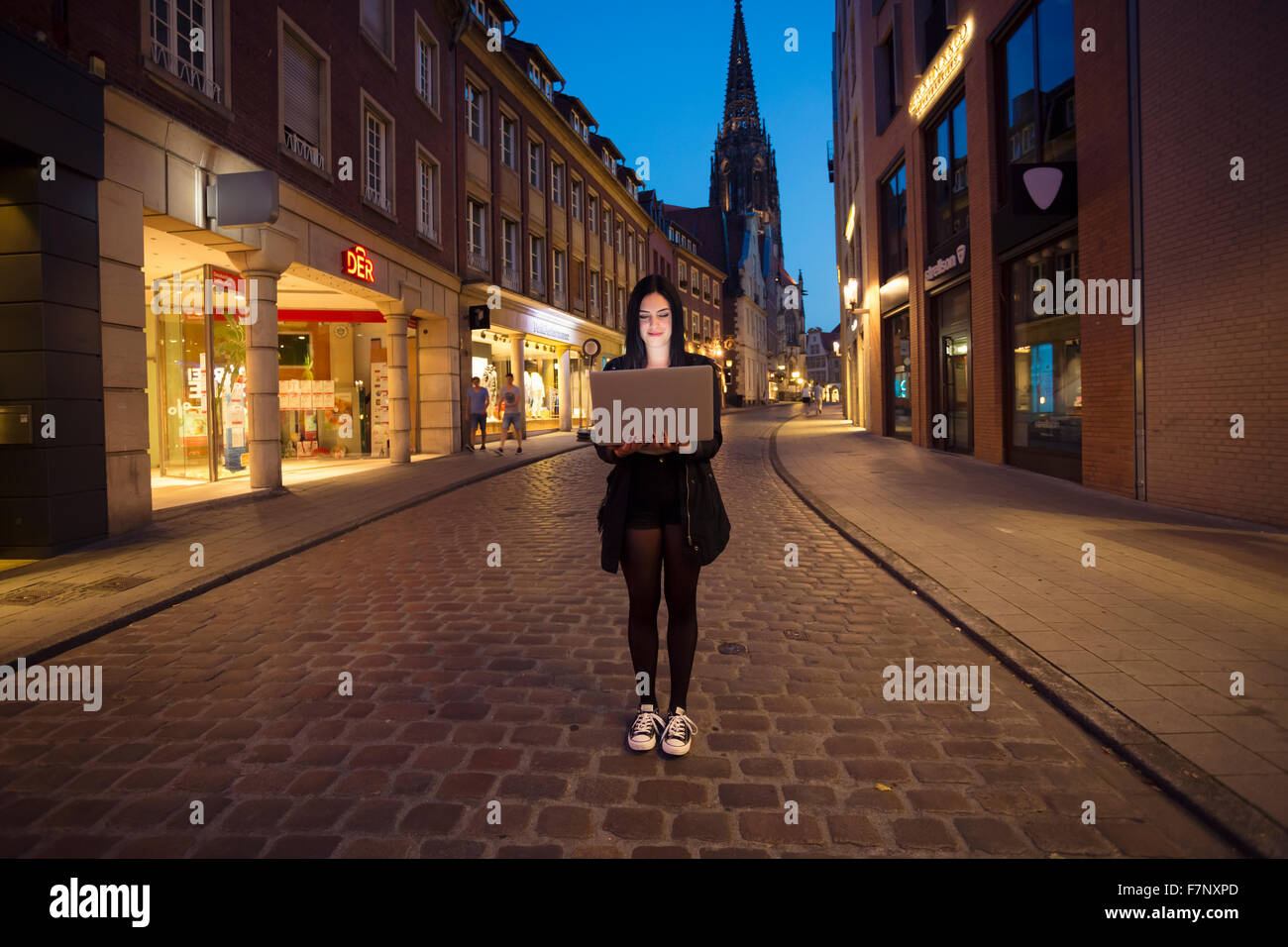 Allemagne, Munster, portrait de jeune femme avec un ordinateur portable dans la ville le soir Banque D'Images