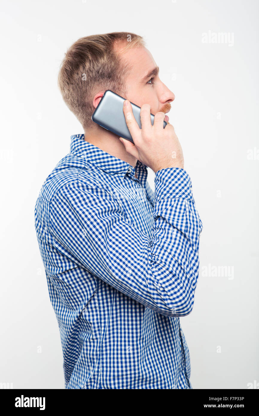 Vue latérale du portrait d'un homme parlant au téléphone isolé sur fond blanc Banque D'Images