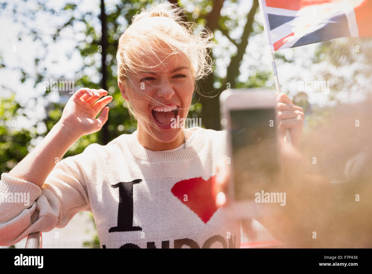 Femme enthousiaste agitant drapeau britannique photographiée Banque D'Images