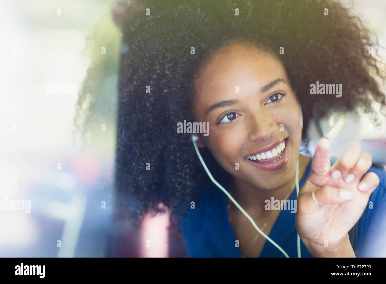 Femme souriante avec afro et des écouteurs en forme de coeur dessin sur bus window Banque D'Images