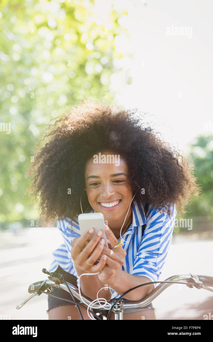 Femme souriante avec afro écoutez de la musique avec des écouteurs et un lecteur mp3 sur location Banque D'Images