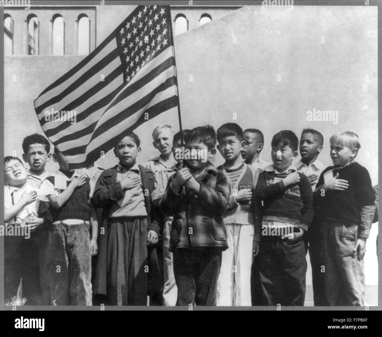 Impression photographique - San Francisco, Californie, avril 1942. Les enfants à l'école publique de Weill pour le soi-disant règlement international et notamment de nombreux Américains, saluant le drapeau. Ils comprennent les personnes évacuées d'origine japonaise qui seront logés dans les centres d'autorité à la réinstallation de la guerre pour la durée. Banque D'Images