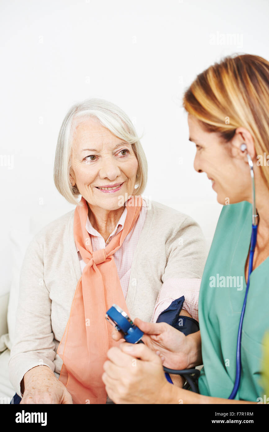 La pression artérielle surveillance infirmière pour senior woman in nursing home Banque D'Images
