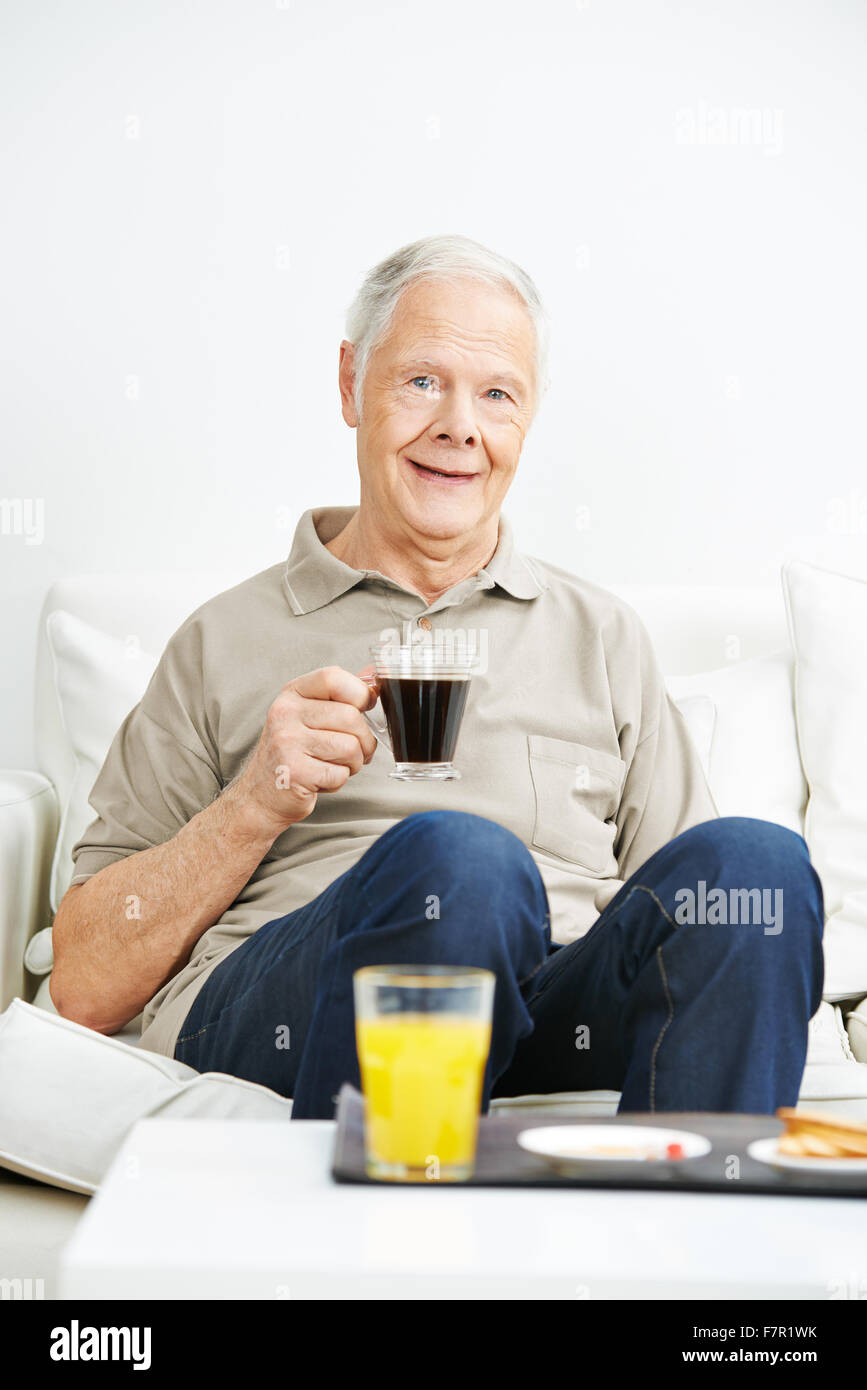 Vieil homme de boire du café pour le petit-déjeuner dans une maison de soins infirmiers Banque D'Images