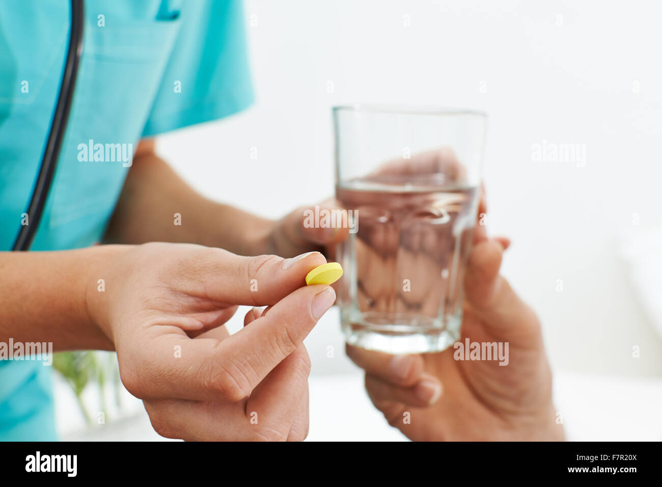 Main de l'infirmière avec des médicaments et un verre d'eau Banque D'Images