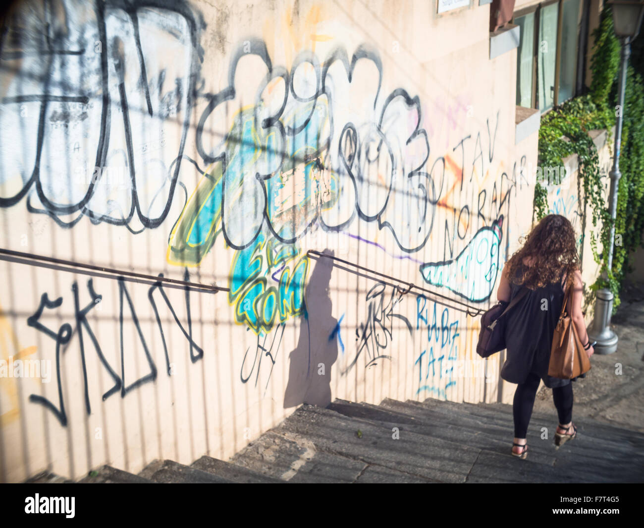 Descente d'escalier au coucher du soleil. Girl retour à l'accueil dans un vol d'étapes avec divers graffiti sur le mur Banque D'Images