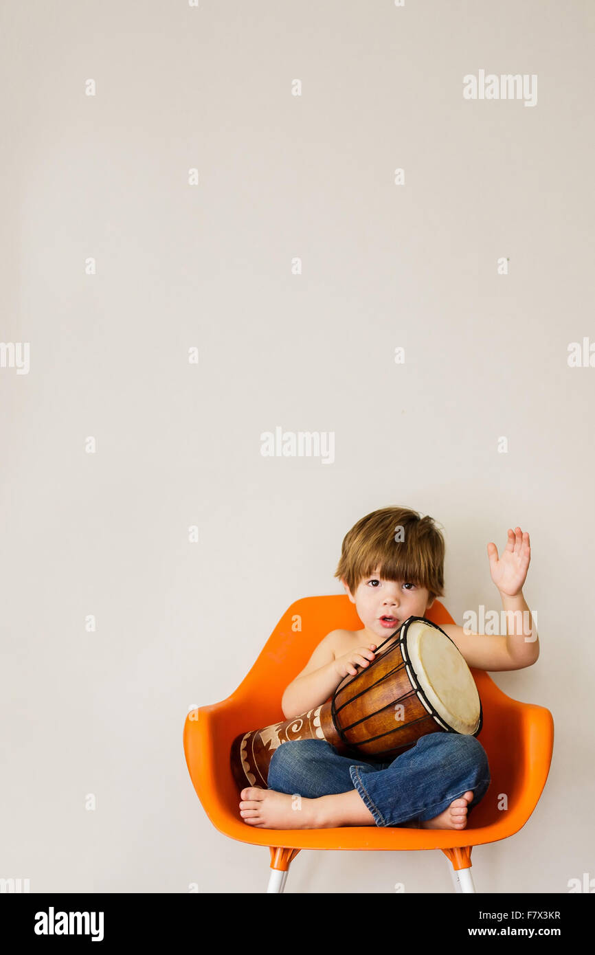 Garçon assis sur une chaise jouant drum Banque D'Images
