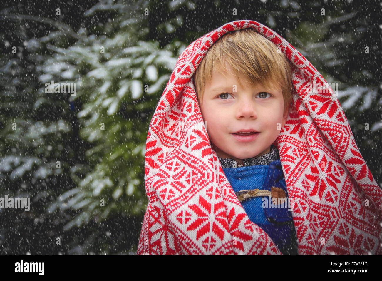 Portrait of smiling boy enveloppé dans une couverture dans la neige Banque D'Images