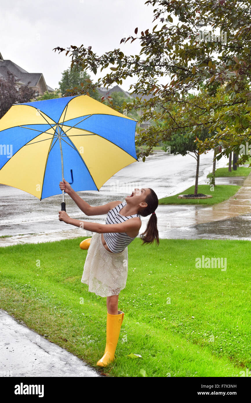 Fille de danser dans la pluie avec un parapluie Banque D'Images