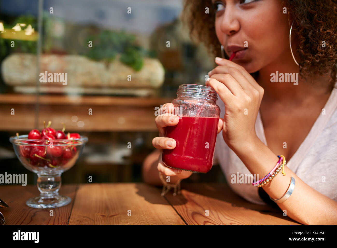Close up image de jeune femme africaine de boire des jus de fruits frais tout en étant assis au café en plein air. Banque D'Images