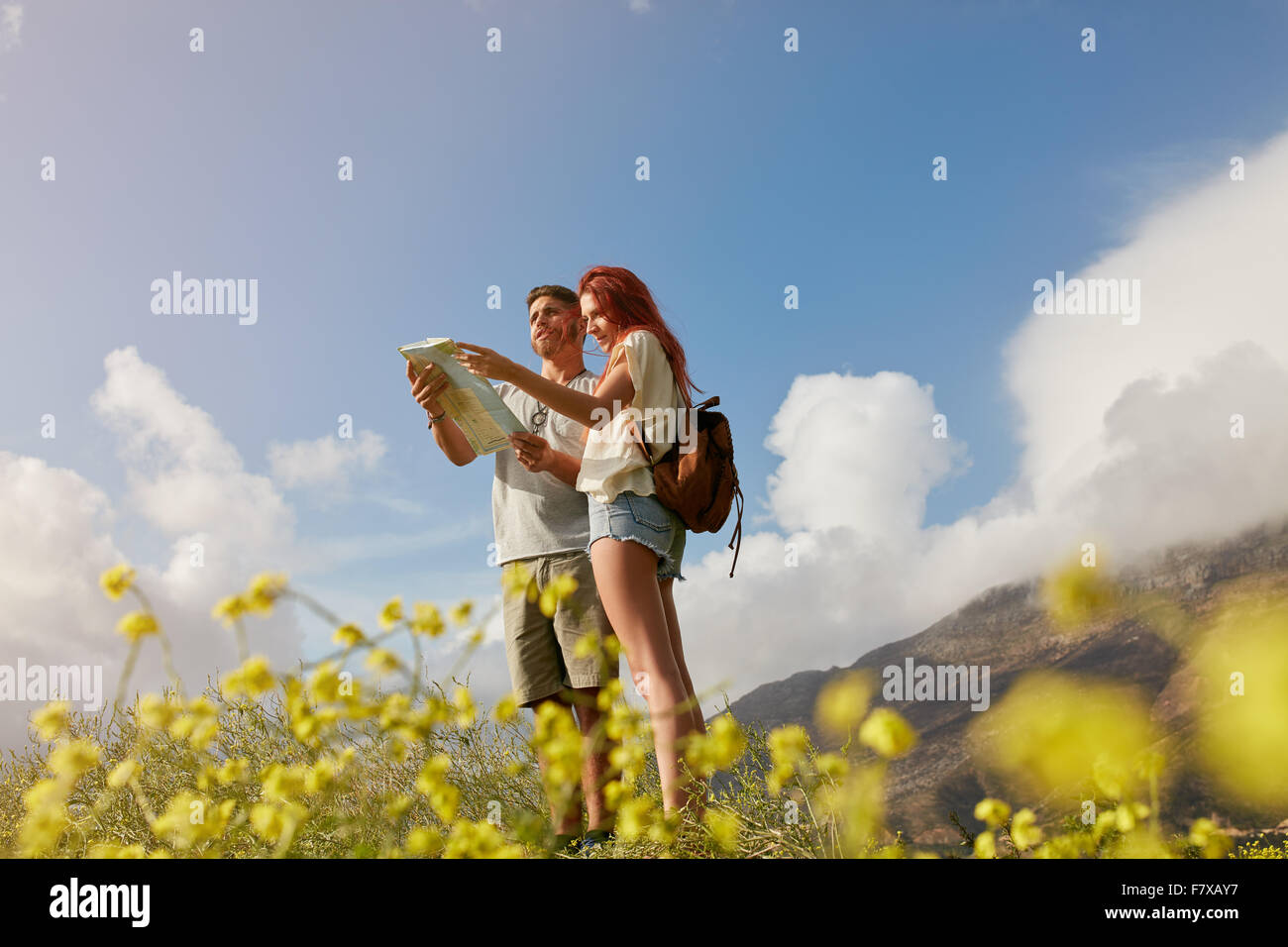 Jeune couple looking at map tout en se tenant à l'extérieur dans la campagne. Couple de randonnée navigation ensemble. Banque D'Images