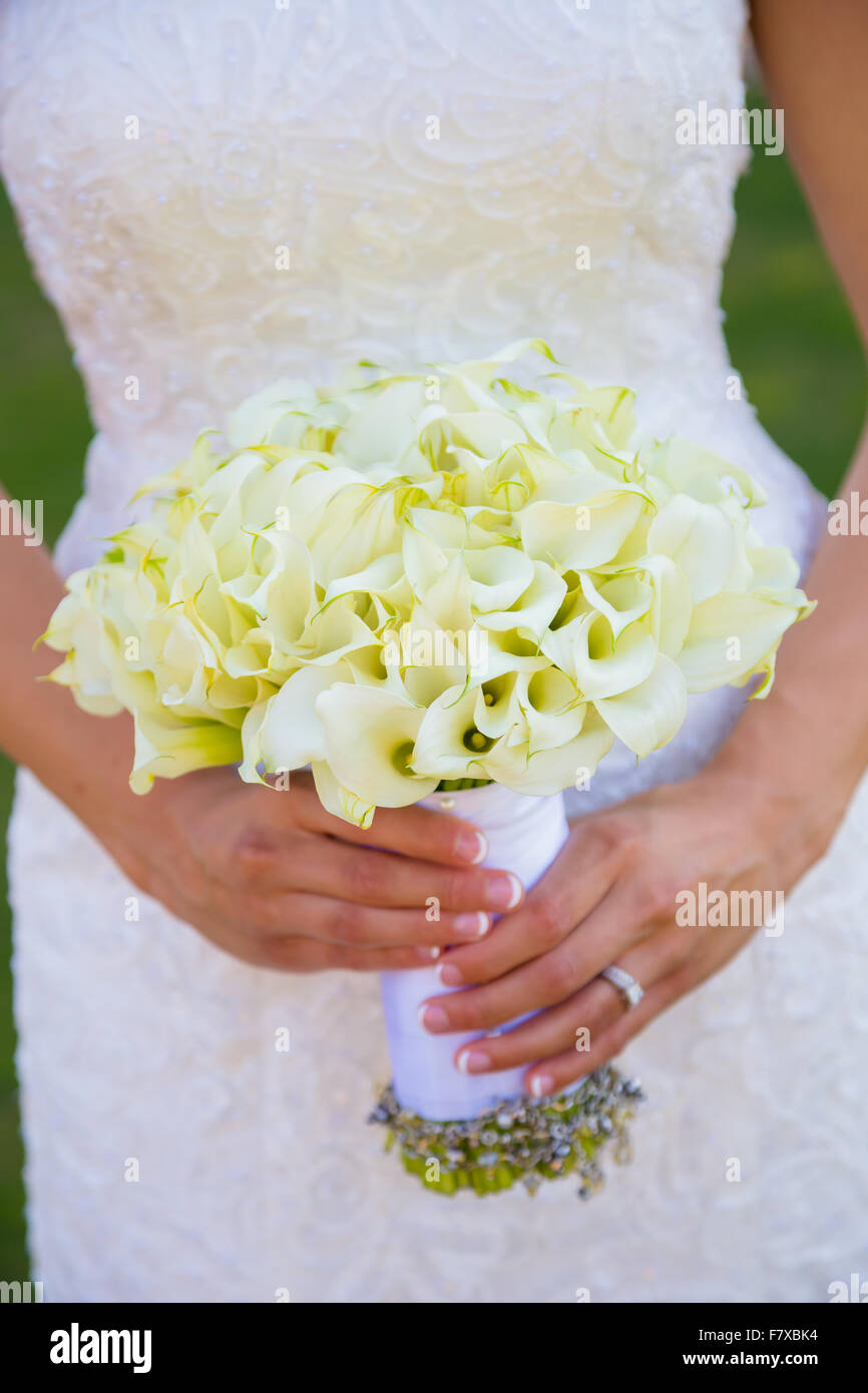 Bride holding bouquet de fleurs avec ses bijoux de sa grand-mère enroulée autour d'elle. Banque D'Images