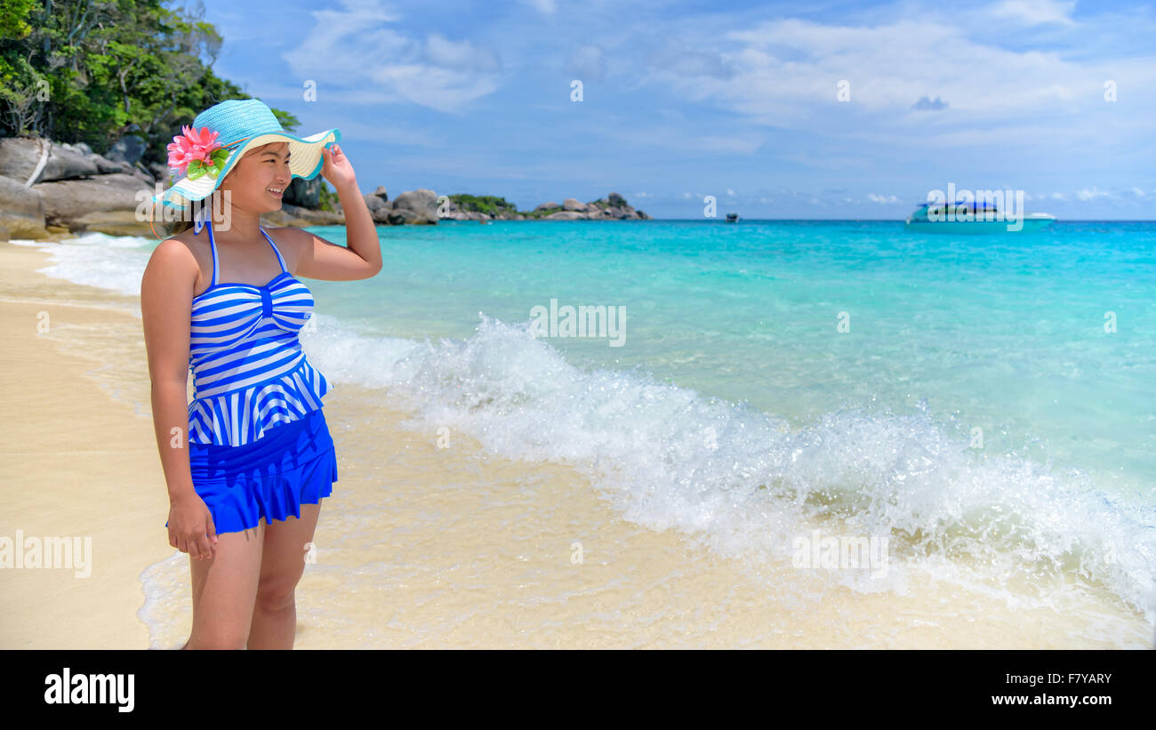 Belle femme dans un maillot rayé bleu et hat postures debout sur la plage de mer sous un ciel d'été à l'île de Koh Miang dans Mu K Banque D'Images