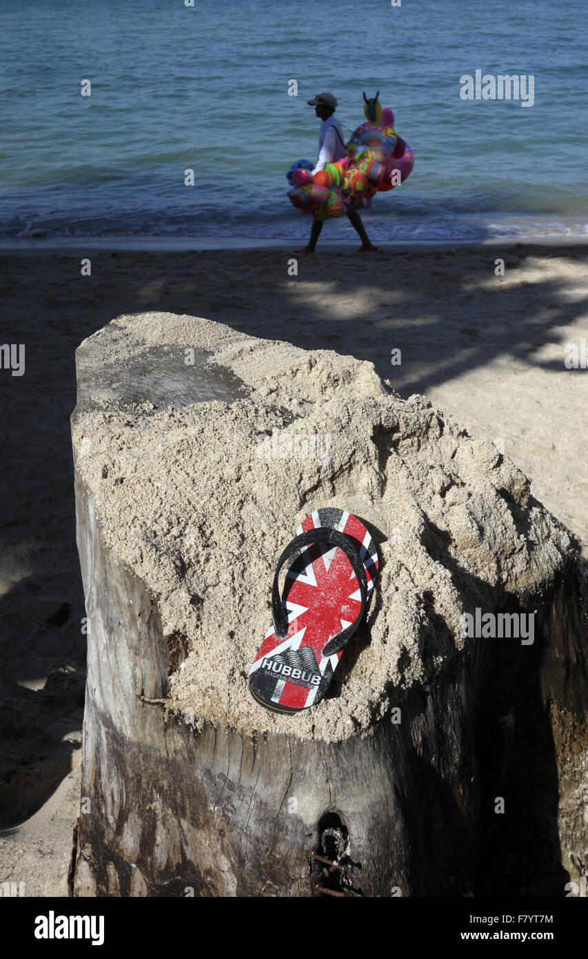 Une seule sandale avec un GO UK Union Jack Flag trouvés conception reposant sur une souche d'arbre couverts de sable sur la plage à Pattaya en Thaïlande Banque D'Images