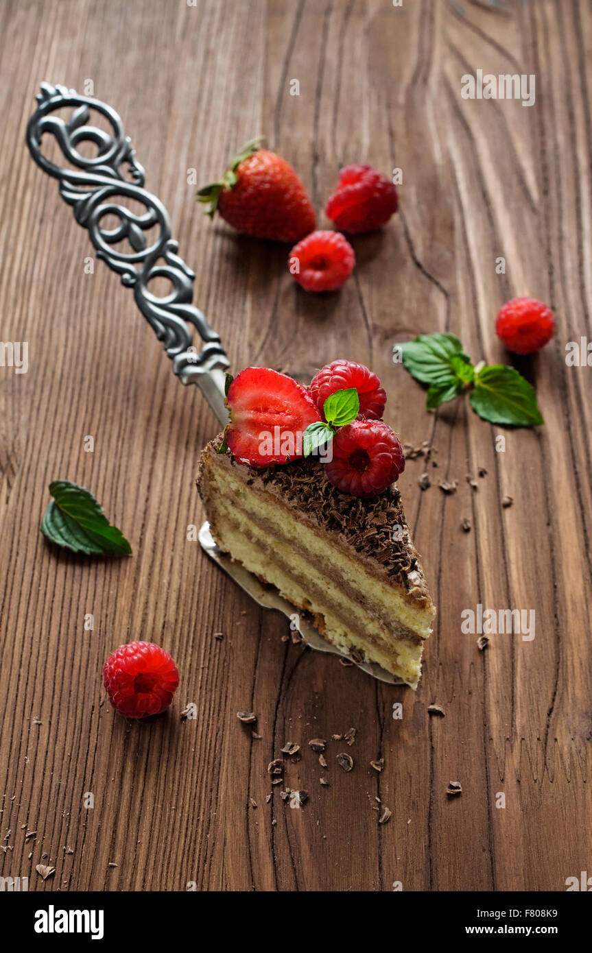 Morceau de gâteau au chocolat avec les baies fraîches sur une spatule vintage Banque D'Images