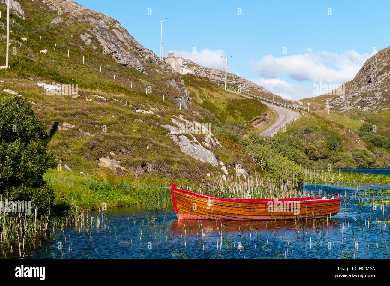 Un petit bateau voguant sur les eaux du Loch Dubh à Tarbet, Sutherland, Scotland. En août. Banque D'Images