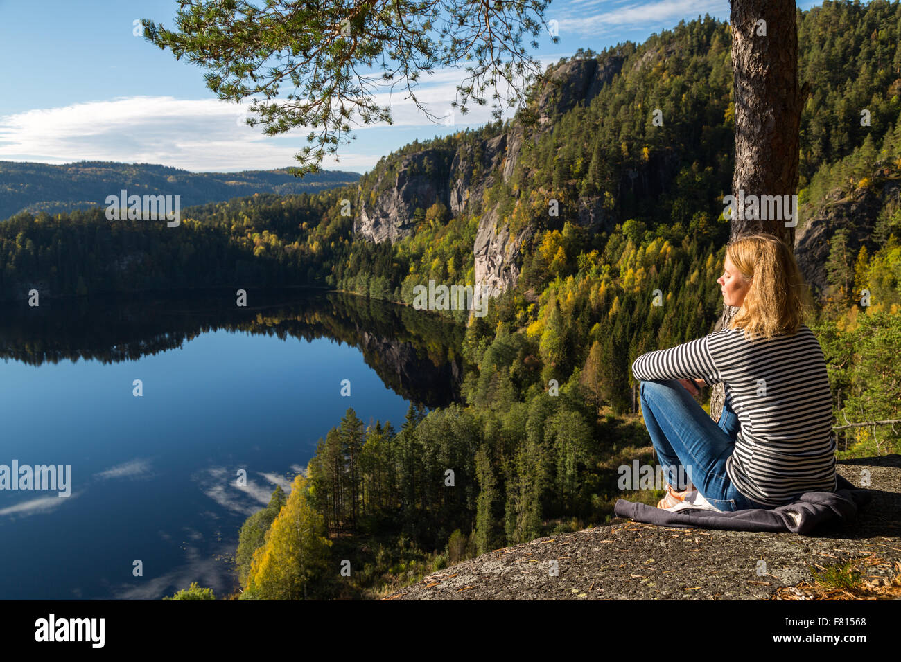 Belle jeune femme contemplant la nature en haut d'une falaise surplombant un magnifique lac Banque D'Images