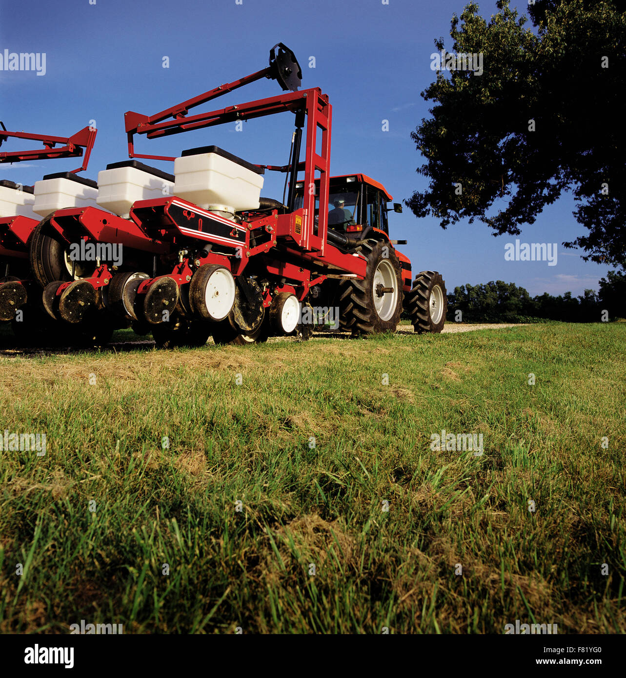 Un semoir agricole moderne et le tracteur se déplace entre les champs agricoles. Banque D'Images