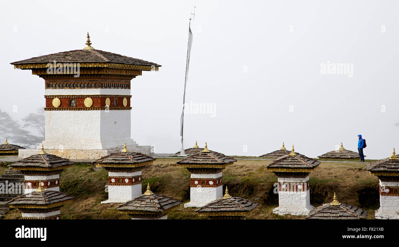 Un homme seul à regarder l'une des 108 Stupas à Dochula Pass en un jour brumeux Banque D'Images