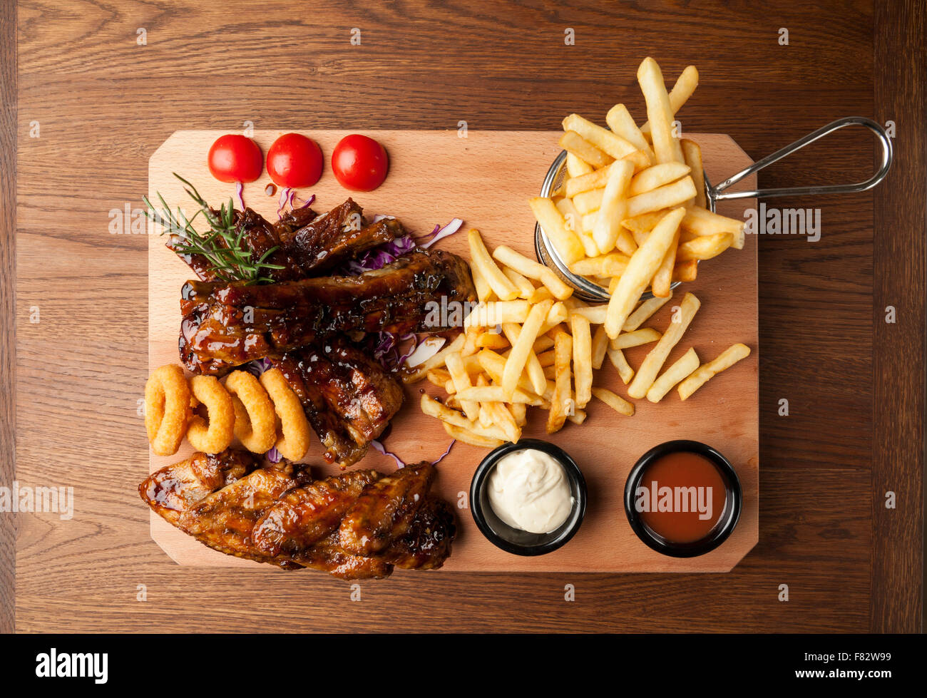 Des ailes de poulet et des côtes avec des frites sur la table en bois Banque D'Images Des ailes de poulet et des côtes avec des frites sur la table en bois Banque D'Images