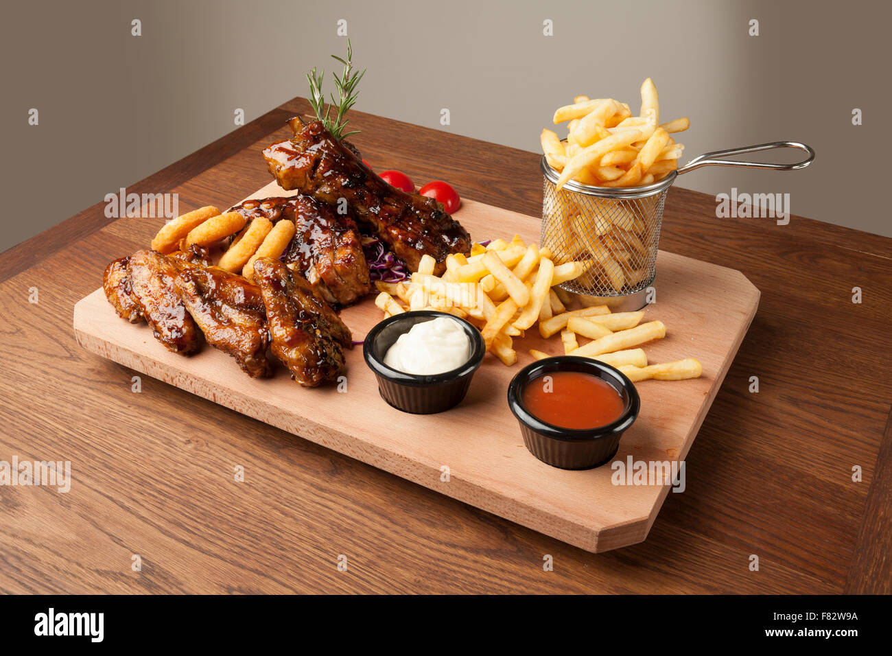 Des ailes de poulet et des côtes avec des frites sur la table en bois Banque D'Images Des ailes de poulet et des côtes avec des frites sur la table en bois Banque D'Images