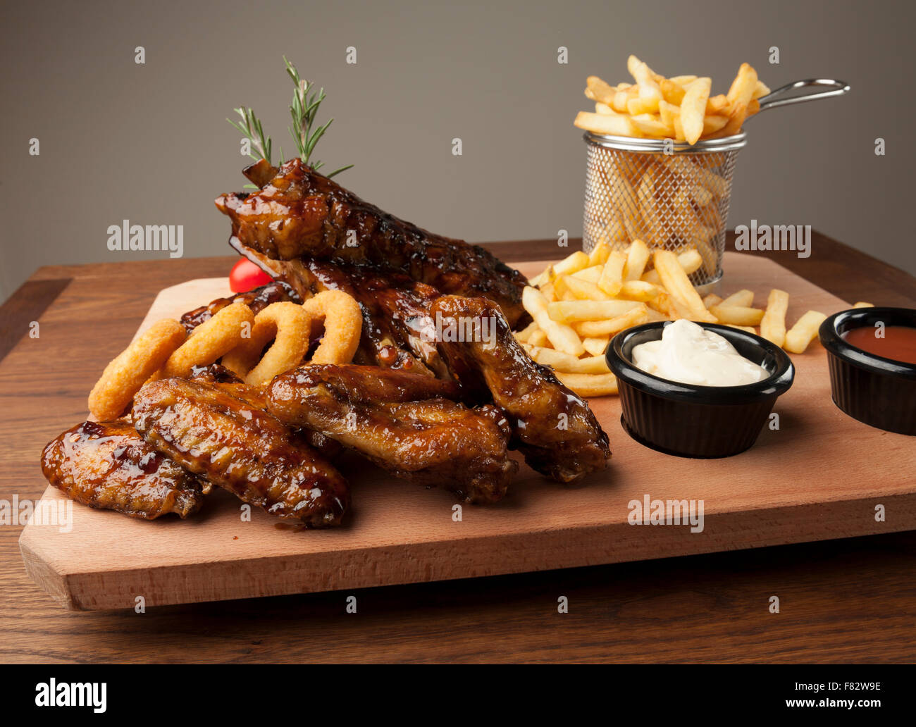 Des ailes de poulet et des côtes avec des frites sur la table en bois Banque D'Images