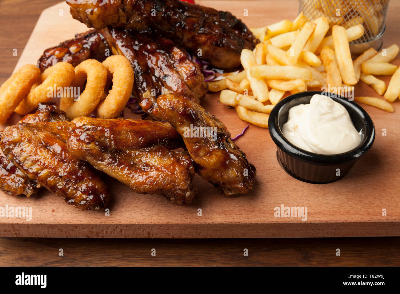 Des ailes de poulet et des côtes avec des frites sur la table en bois Banque D'Images Des ailes de poulet et des côtes avec des frites sur la table en bois Banque D'Images