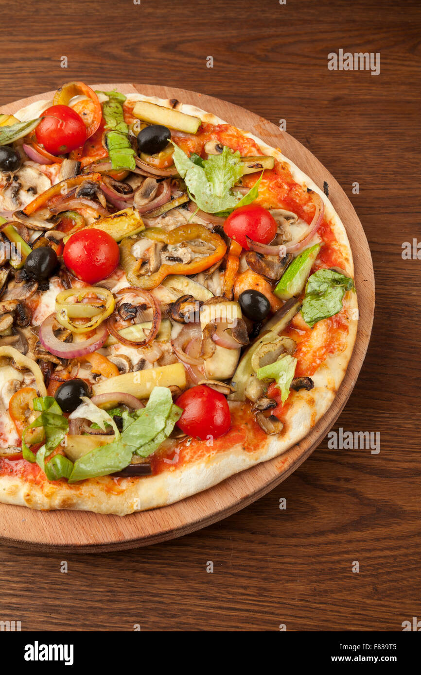 Pizza végétarienne avec des légumes sur plaque de bois Banque D'Images