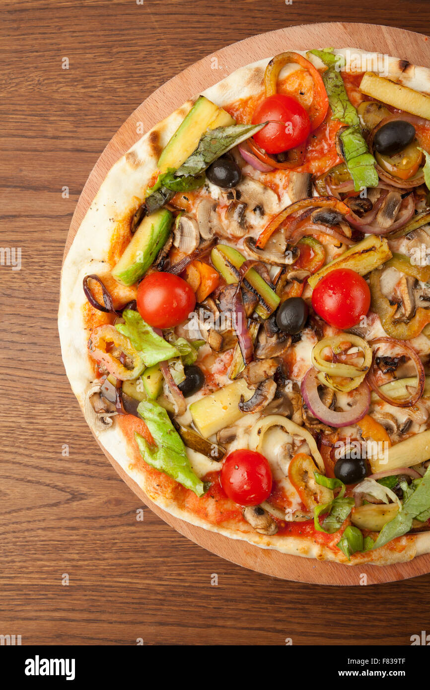 Pizza végétarienne avec des légumes sur plaque de bois Banque D'Images