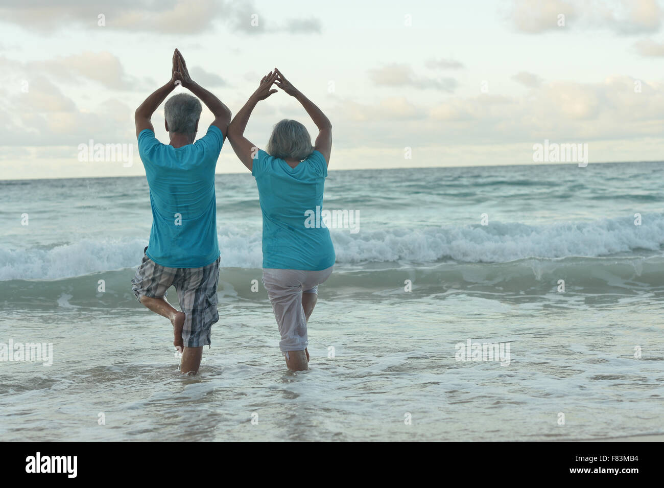 Vieux couple doing yoga on beach Banque D'Images