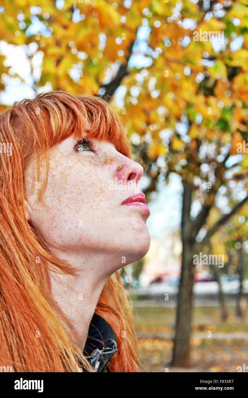 Rouge rêve hair girl face avec rousseur sur fond de feuillage d'automne. Banque D'Images