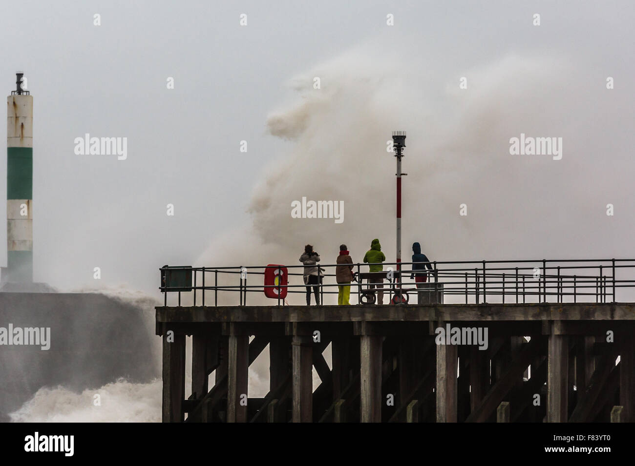 Pays de Galles, Royaume-Uni. Le 05 décembre 2015 un groupe de piétons tenir près de l'énormes vagues qui sont battues la jetée en béton que Storm Desmond apporte force de coup de vent et une mer agitée à Aberystwyth. Crédit : Ian Jones/Alamy Live News Banque D'Images