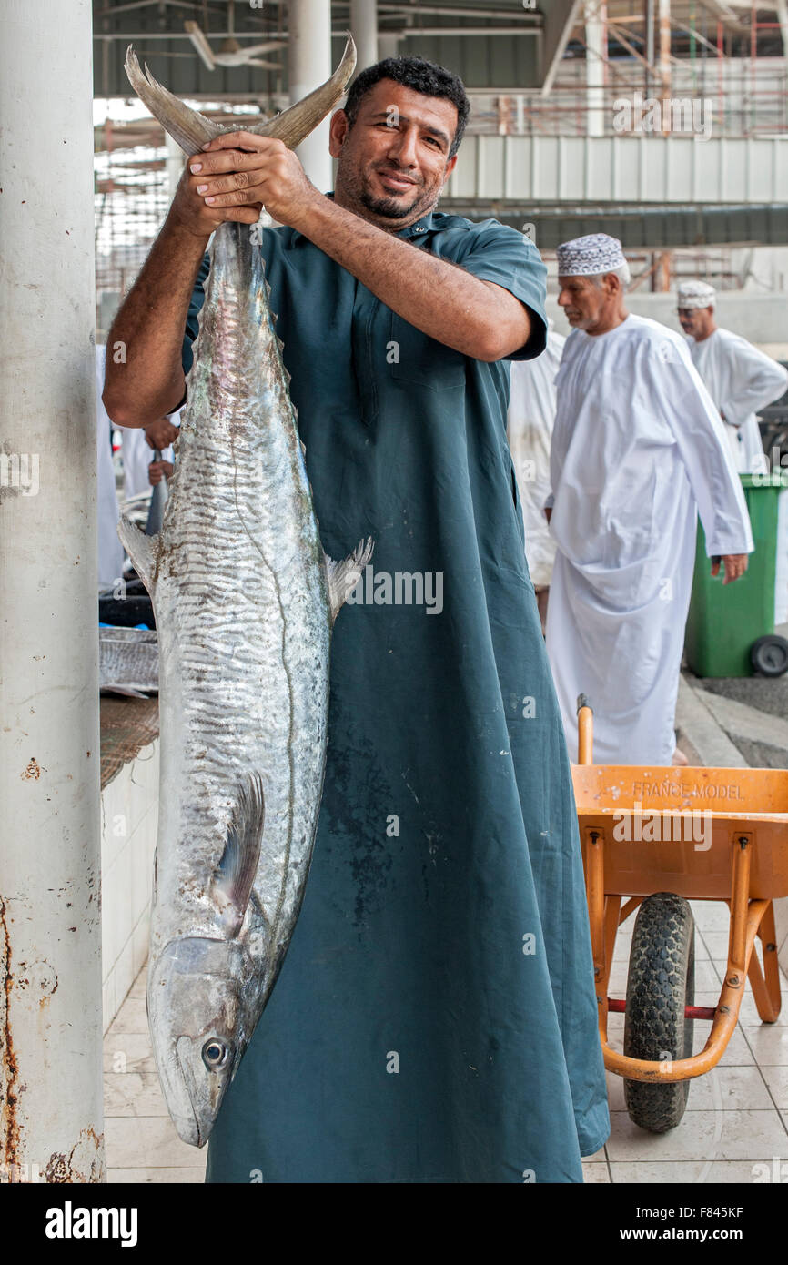 Omani homme posant avec un poisson dans le marché aux poissons de Mutrah à Muscat, capitale du Sultanat d'Oman. Banque D'Images