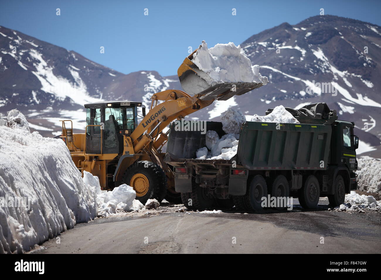 Route de compensation de la neige sur une route de haute altitude des Andes, dans le Chili. Le chargement d'une excavatrice camion avec la neige. Banque D'Images