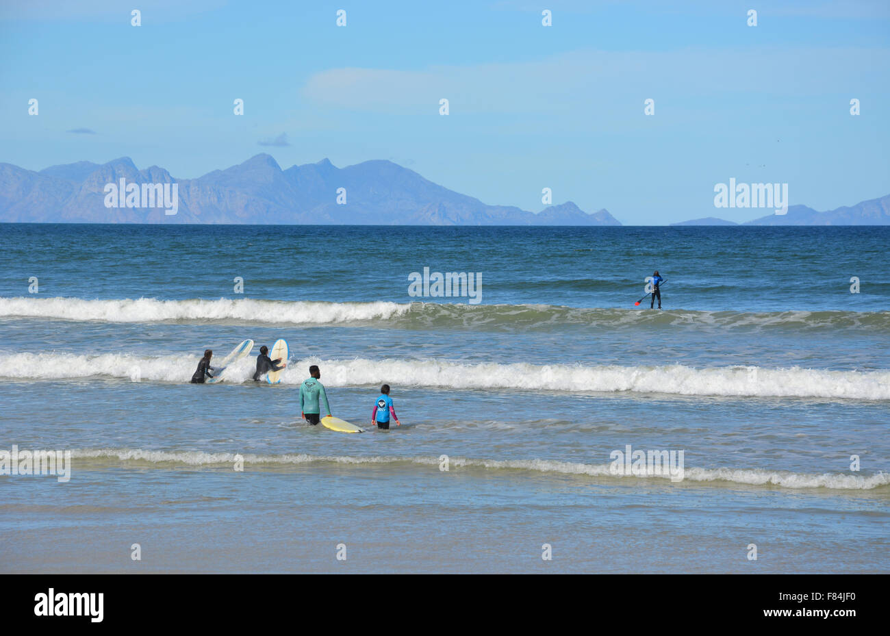 Les surfeurs dans l'eau de la baie de False à Muizenberg Beach, Afrique du Sud Banque D'Images