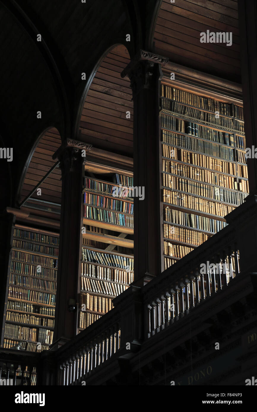 Livres anciens sont stockés sur les étagères à l'intérieur de la longue pièce de l'ancienne bibliothèque du Trinity College de Dublin, Irlande Banque D'Images
