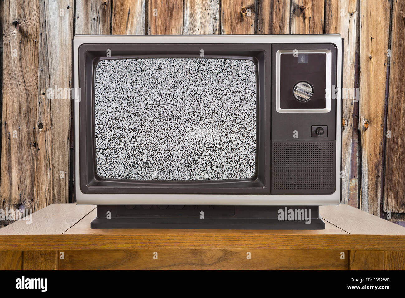 Vieille télévision portable avec écran statique et mur en bois rustique. Banque D'Images